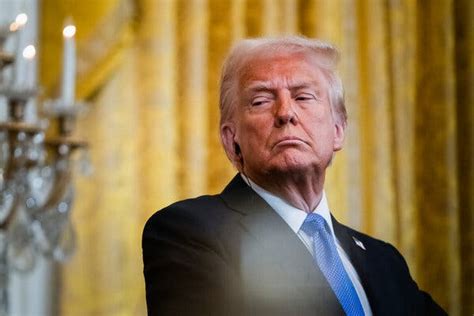 US President Donald Trump, wearing a dark blue suit, white shirt, and light blue tie, looks ahead, h