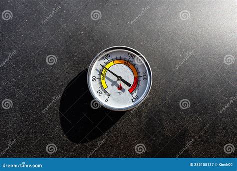 A Round Thermometer Showing 80 Degrees Celsius Placed on a Charcoal ...