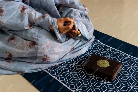 A muslim woman sitting on a prayer mat and holding prayer beads for ...