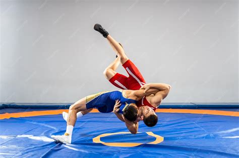 Two young men in blue and red wrestling tights are wrestlng and making ...