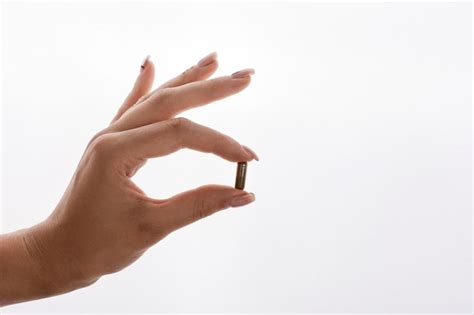 Woman holds in her hand a capsule with vitamins or oil | Free Photo