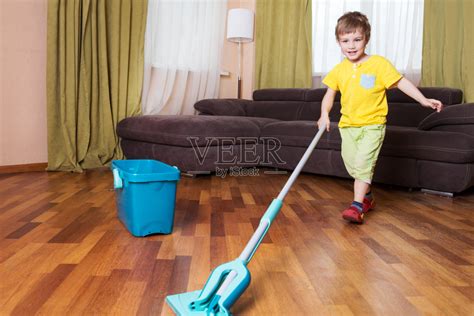 男孩在房间里打扫地板。男孩帮助妈妈打扫卫生。照片摄影图片_ID:300228429-Veer图库