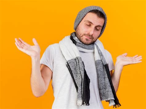 With closed eyes young ill man wearing winter hat and scarf spreading ...