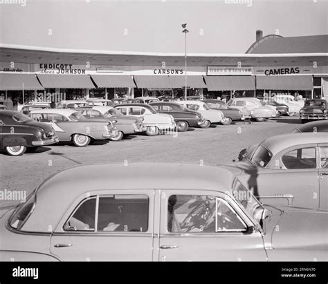 1950s parking lot FULL OF CARS AT strip mall with shoe store camera ...