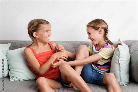 Young girls tickling each other on sofa Stock Photo | Adobe Stock