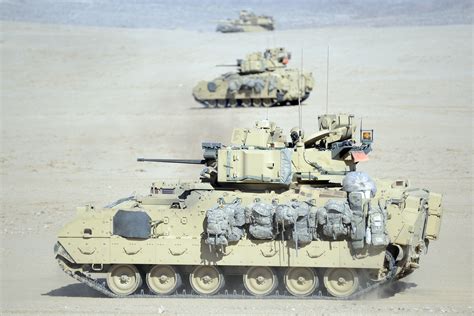 A M1-A1 Abrams tank and M2 Bradley fighting vehicles conduct a bounding ...