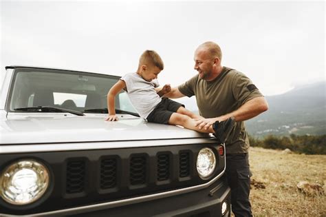 Pai e filho brincando no capô de um carro em uma viagem | Foto Premium