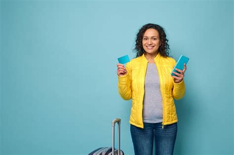 Smiling african woman in yellow jacket stands against blue wall ...