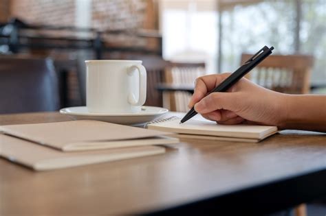Closeup image of a hand writing on blank notebook with coffee cup on ...