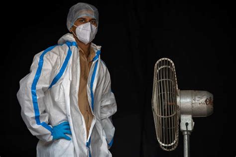 A health worker in personal protective equipment (PPE) takes a break ...