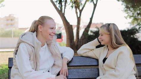 Adult daughter talking to her senior parents on a bench in a park