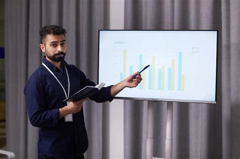 Confident bearded coach in dark blue formal wear pointing at charts on ...