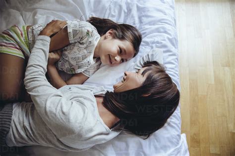 Mother and daughter cuddling on a bed in a kids room