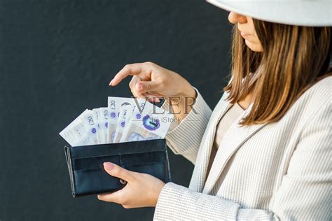 年轻的女商人拿着黑色钱包，手握英镑，女性手的特写。现金支付、储蓄和工资的概念照片摄影图片_ID:421774890-Veer图库