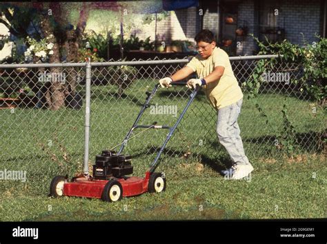 Austin, Texas USA,1988: Hispanic boy, 13, mowing lawn with gas-powered ...