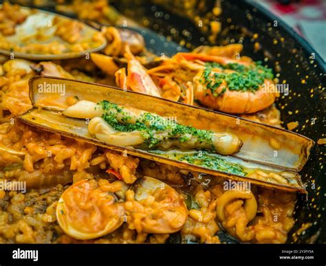 The traditional Spanish seafood dish called Paella in a black pan with ...