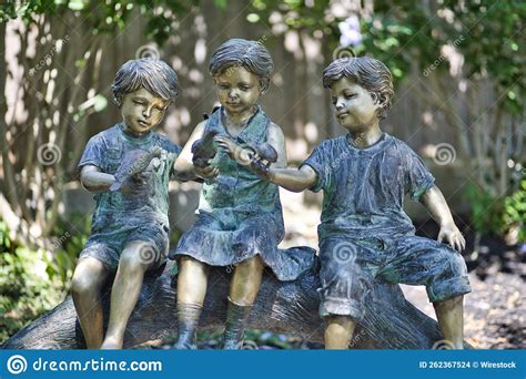 Colored outdoor statue of a child pressing their forehead on the hand of a seated elder