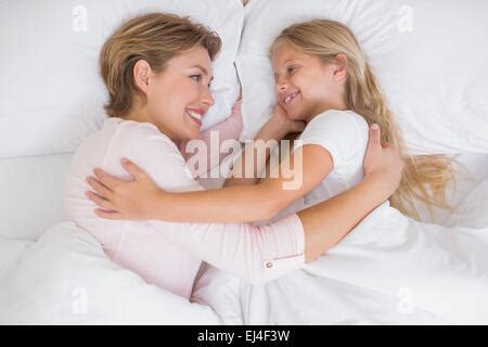 Mother and daughter cuddling on a bed in a kids room