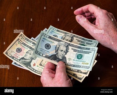 Man counting American (US) money with five, ten & twenty dollar bills ...