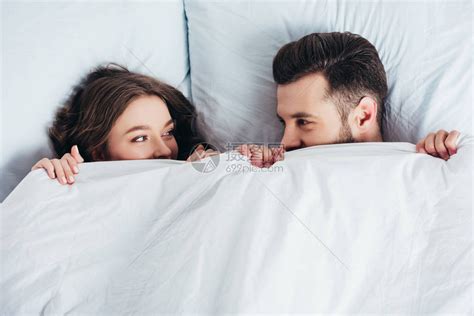 爱的年轻夫妇躲在毯子下躺在床高清图片下载-正版图片503369396-摄图网