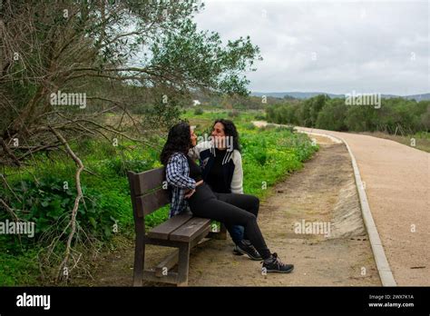 Adult daughter talking to her senior parents on a bench in a park