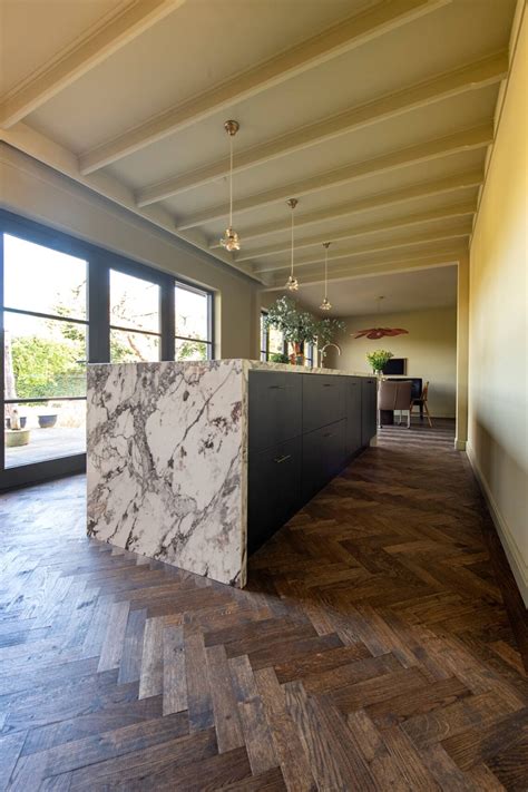 Dark herringbone floor with black kitchen with marble countertops