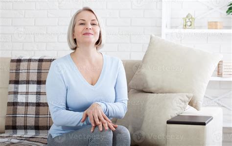 Smiling mature woman sitting on her sofa 17400612 Stock Photo at Vecteezy