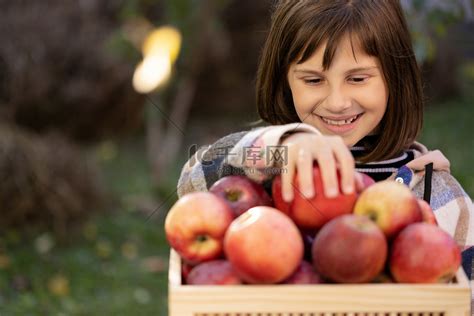 小学生女孩的手拿红苹果吃苹果。高清摄影大图-千库网
