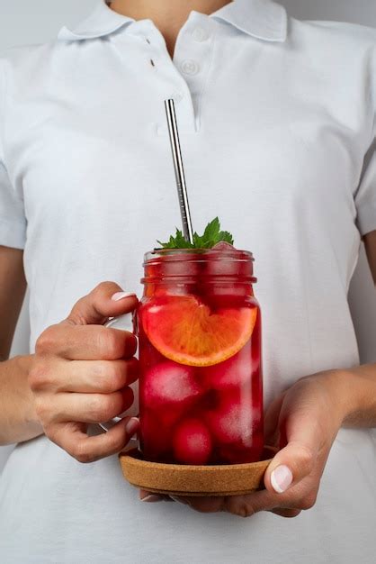 Person, die Hibiskus-Eistee in einem durchsichtigen Glasbehälter hält ...