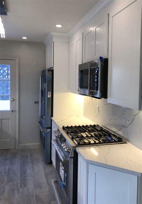 White shaker cabinetry mixed with marble look quartz countertops and ...
