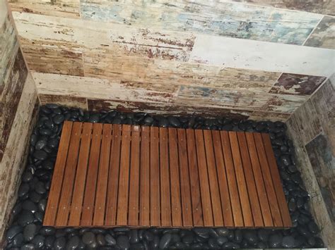 Teak wood shower floor surrounded by river rock, walls tiles in ceramic ...