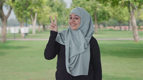 Happy Muslim woman showing victory sign in park | Premium Stock Video ...
