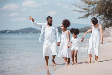 African American family walking together on the beach on holiday ...