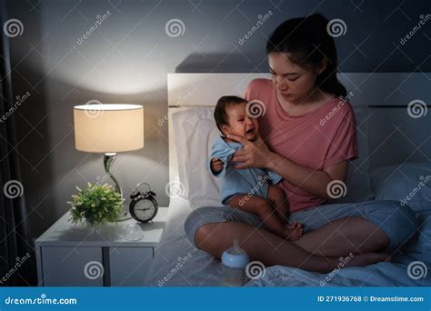 Mother Holding Burping and Crying Baby after Feeding Milk on Bed at ...