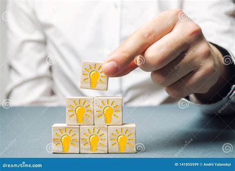 A Businessman Puts Wooden Blocks with a Light Bulb of an Idea or ...