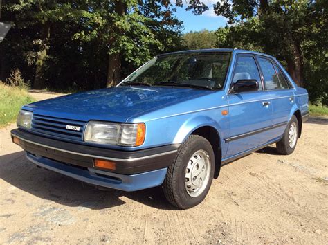 Download "classic Mazda 323 Glowing On Mountain Road" Wallpaper | Wallpapers.com