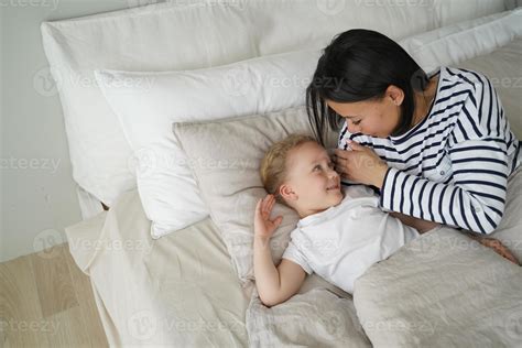 Young mom lying in bed with little kid daughter after sleeping in ...