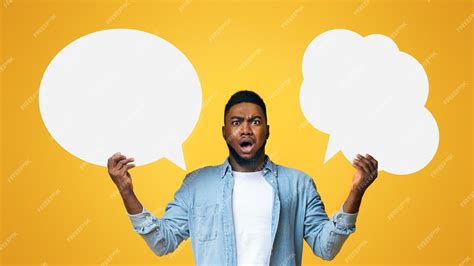Confused black guy holding two speech bubbles on yellow background ...