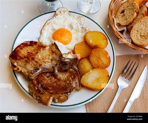 Pork chop with potatoes and scrambled eggs Stock Photo - Alamy
