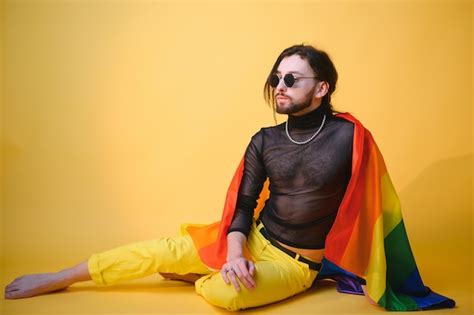 Gay man hold rainbow striped flag isolated on colored background studio ...