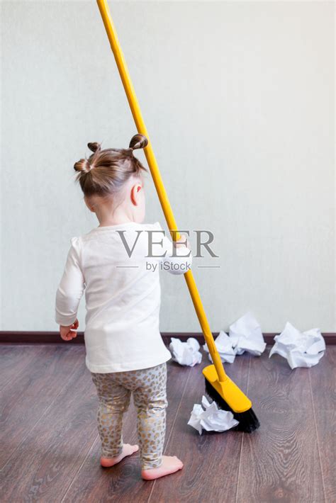 一个1.5岁的女孩手里拿着一把扫帚，打扫房子的概念，打扫公司，打扫空间，极简主义照片摄影图片_ID:315872714-Veer图库