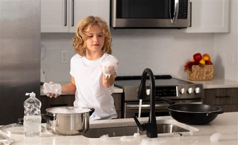 Child boy washing dishes in the kitchen interior dishwashing liquid ...