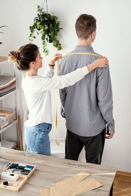 Weiblicher Schneider, der männliches Kundenhemd misst | Kostenlose Foto