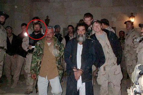 Black-and-white photo of Saddam Hussein, in a suit, with a group of women students