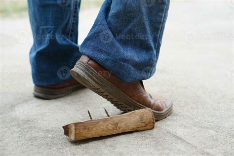 Closeup man wears shoes is stepping on rusty metal nail on wood. Concept, unsafe , risk for ...