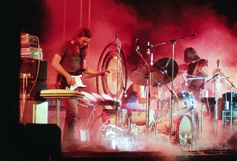 Pink Floyd playing on the stage surrounded with a smoke and illuminated ...