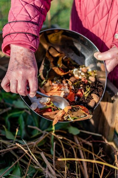Persoon die in een compostbak wat keukenafval zoals groenten, fruit ...