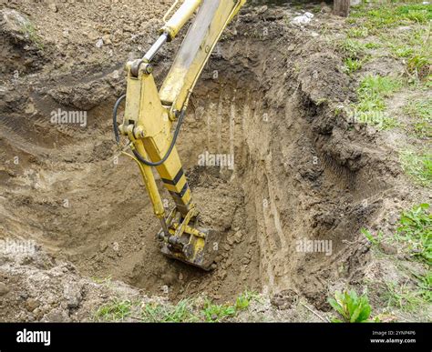 A yellow excavator digging a deep trench in the soil, showcasing heavy equipment in action at a ...
