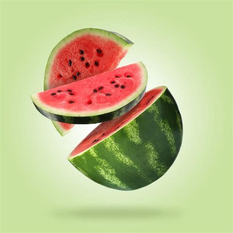 Cut juicy watermelon falling on light green background | Premium Photo