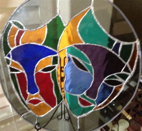a stained glass sun catcher with two faces on it's face and the bottom ...